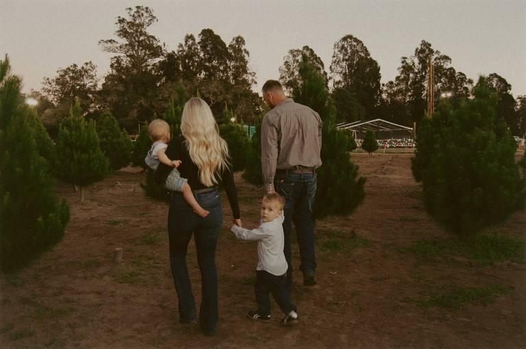 Family walking together through a tree farm at dusk